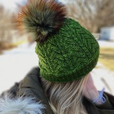 a woman wearing a green hat with a fur pom