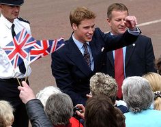 two men standing next to each other in front of a group of people with flags