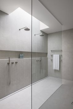 a walk in shower sitting next to a white tiled wall and counter top under a skylight