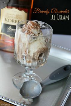 an ice cream sundae in a glass on a tray with a bottle and spoon