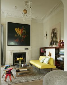 a living room filled with furniture and a painting on the wall above it's fireplace