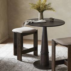 a round table with two stools and a vase on top