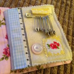 several pieces of fabric and sewing tools are on a table cloth with measuring tape, scissors, and buttons