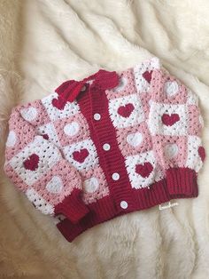 a pink and white sweater with hearts on it sitting on a furnishing surface