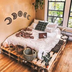 a bed sitting on top of a wooden pallet in a bedroom next to a window