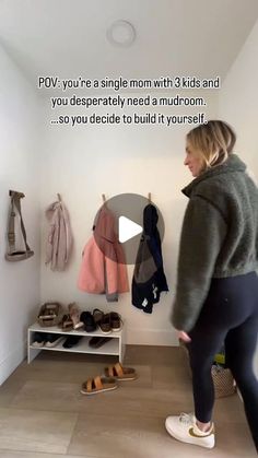 a woman standing in front of a wall with shoes on the floor and clothes hanging up