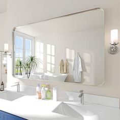 a bathroom with blue cabinets and white counter tops is pictured in this image, there are two mirrors on the wall above the sink