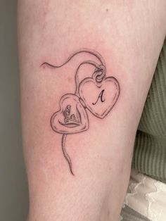 a woman's arm with two hearts and the letter i tattooed on her left leg