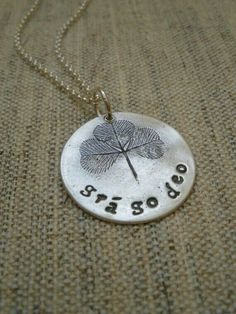 a silver necklace with a leaf on it that says,'good luck'and the word