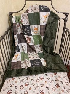 a baby crib with a blanket that has animals on it, and a name tag