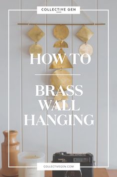 the words how to brass wall hanging above a table with a camera and vase on it