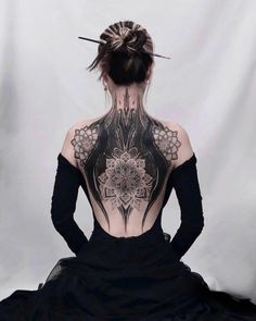 a woman with tattoos on her back sitting down