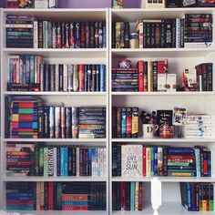 a book shelf filled with lots of books on top of white shelves next to a window