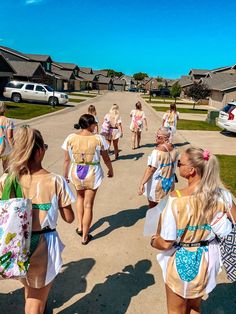 several girls in bathing suits walking down the street with their back to the camera bags