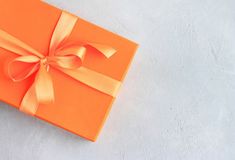 an orange gift box with a bow on the top and ribbon around it stock photos