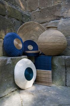 several baskets and vases are sitting on the ground near a stone wall in an outdoor setting