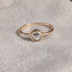 a gold ring with a white diamond in the middle on top of a gray surface