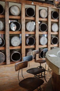 there are many chairs and tables in the room with barrels on the wall behind them