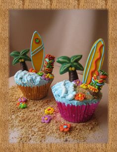 two cupcakes decorated with surfboards and palm trees