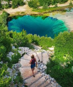 a woman is walking up some steps towards a blue lake