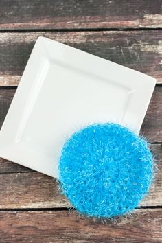 a white plate topped with a blue fuzzy ball sitting on top of a wooden table