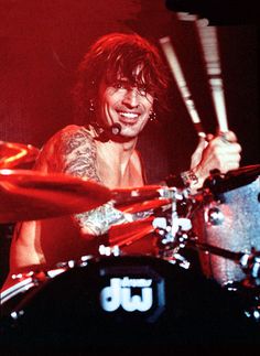 a man with long hair playing drums on stage