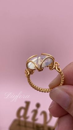 a hand holding a gold ring with two pearls on it's side and the words diy written below