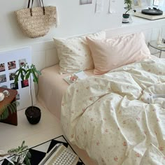 a bed with pink sheets and pillows in a white room next to a potted plant