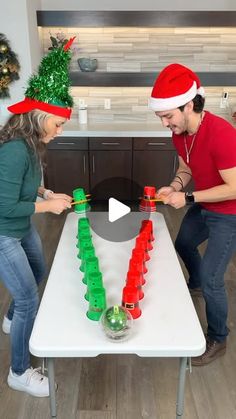 two people in santa's hats are playing with legos on a white table