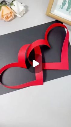 two hearts cut out of paper sitting on top of a table