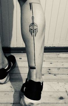 a black and white photo of a person's legs with an arrow tattoo on it