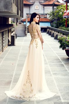 a woman in a long dress is standing on the sidewalk with her back to the camera