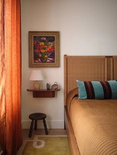 a bedroom with a bed, nightstand and painting on the wall