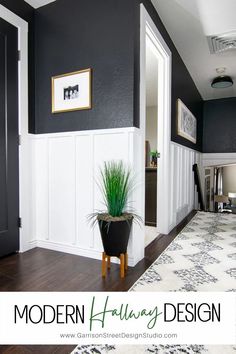 a black and white hallway with a potted plant on the floor next to it