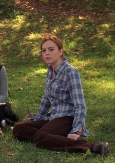 two women sitting on the grass in front of trees