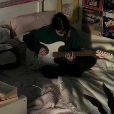 a person sitting on a bed playing an electric guitar