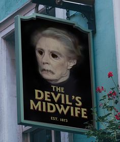 the devil's midwife sign is hanging from the side of a building