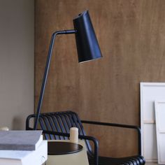 a black lamp sitting on top of a table next to a chair and book shelf