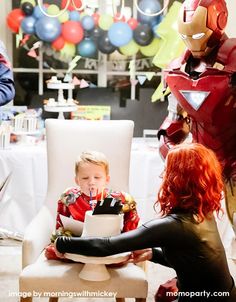 a little boy sitting in a chair at a birthday party