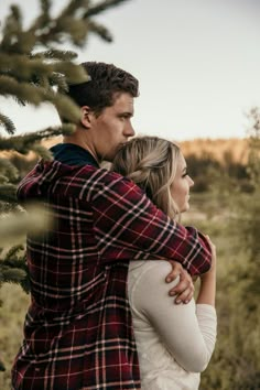 a man and woman hugging in front of a tree