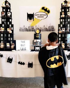 a young boy dressed up as batman standing in front of a table with decorations on it