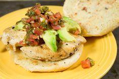 a yellow plate topped with an open face sandwich and a tortilla roll covered in toppings