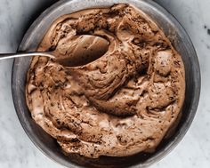 a bowl filled with chocolate ice cream on top of a marble counter next to a spoon