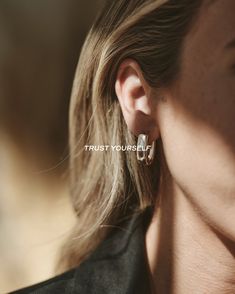 a woman wearing earrings with the words trust yourself on it