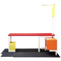 an orange, yellow and white table with two drawers on it's sides next to a lamp