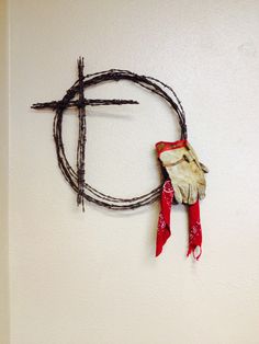 a cross made out of branches and tied to the wall with a red ribbon around it