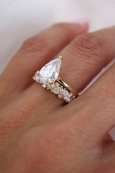 a woman's hand with a diamond ring on top of her finger and an engagement band