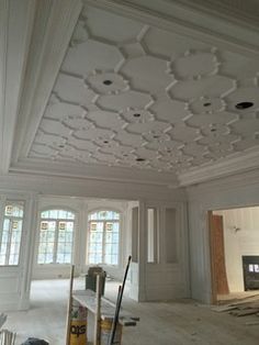 an empty room with white walls and ceiling tiles on the floor is being worked on