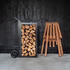 a pile of wood sitting next to a cart full of logs on top of a cement floor