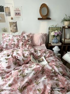 a bed with pink and green floral comforter on top of it next to a wooden nightstand